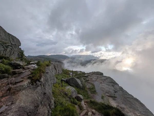 Yüksek açılı görüntü büyük bir uçurum kenarını ve derin bir fiyort örtülü ağır sis ve alçak bulutlar altında bulutlu bir gökyüzü.