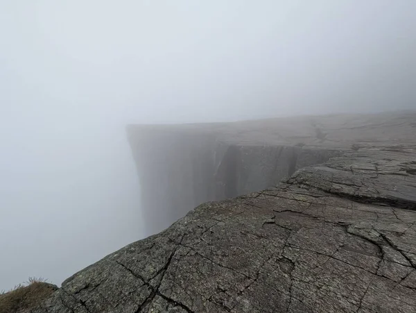 Yoğun siste kaybolan kayalık kenar.