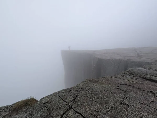 Yoğun siste bir dağın tepesinde bir insanın silueti..