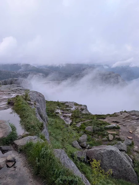 Vadinin üzerindeki kayalık uçurumlar ve bulutlarla puslu dağ manzarası.