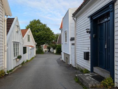 Stavanger, Norveç. Geleneksel beyaz ahşap evler kırmızı çatılı dar kaldırımlı cadde boyunca yumuşak akşam gökyüzünün altında..