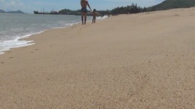 Baba ve bebek sahilde gidin. dalga kıyıya alır. yumuşak kum plajıdır