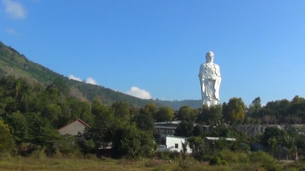 Високий білий Будди стоїть на тлі блакитного неба. Панорама. Храм стоїть на горі. — стокове відео