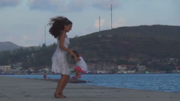 Une belle jeune fille dansant avec un bébé sur le front de mer à côté de la mer — Video