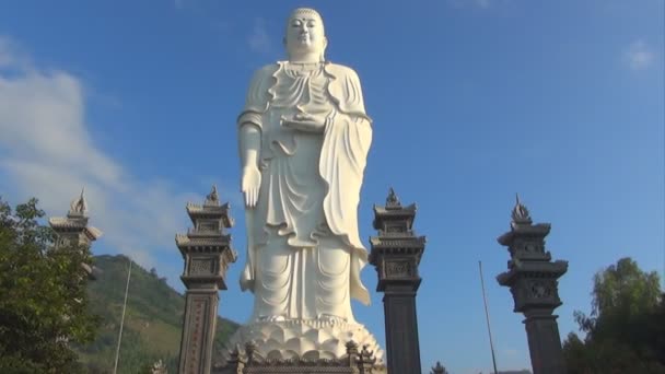 High white Buddha stands on a background of blue sky. clouds race across the sky. Timelapse. — Stok video