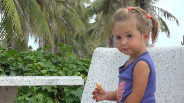 Girl eats bread and sitting on a bench — Stock Video