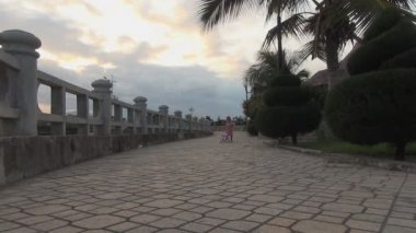 Küçük kız iterek oyuncak bebek arabası. Güvertede yürüyüş elbiseli kız
