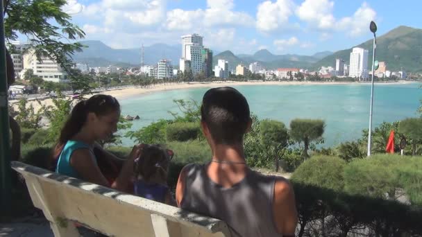 Jeune famille reposant sur le banc sur la colline surplombant la mer . — Video