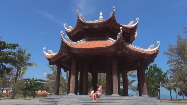 Madre e hija sentadas en escalones de hermoso edificio budista con columnas — Vídeo de stock
