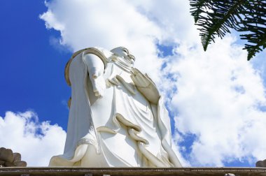 Mavi gökyüzü arka plan üzerinde beyaz Buda ayakta