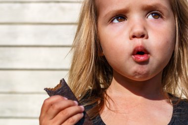 little girl eats tasty chocolate clipart