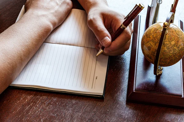 Man writes with his left hand in the diary entries. — Stock Photo, Image