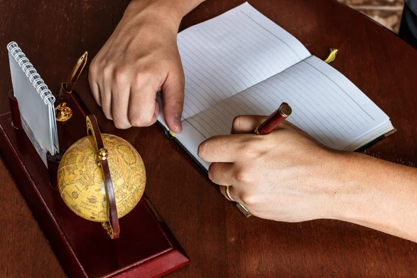 Man schrijft met zijn linkerhand in het dagboek. — Stockfoto