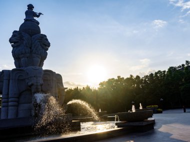 Çeşme, topa oturan çocuk ve flüt çalmaya, su kaçar mayo filler dan