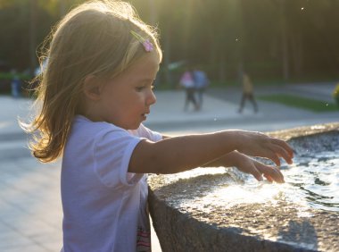 Çeşme ellerini yıkama güzel küçük bir kız. Sunset Bulvarında. ciddi düşünceli yüz.