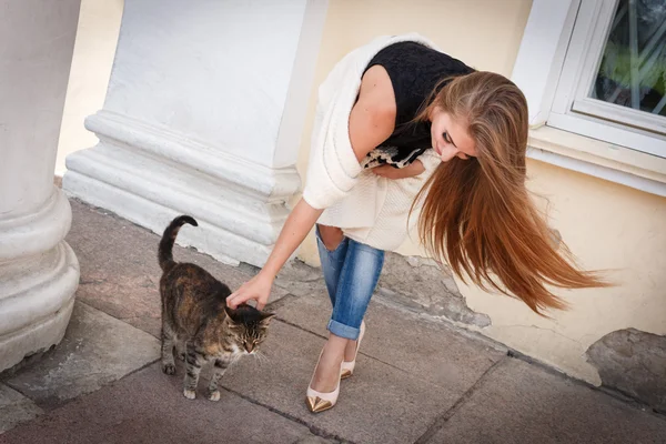 Moda de agradável muito jovem hipster mulher brincando com um gato, ele inclinou-se para baixo, cabelo voando . — Fotografia de Stock