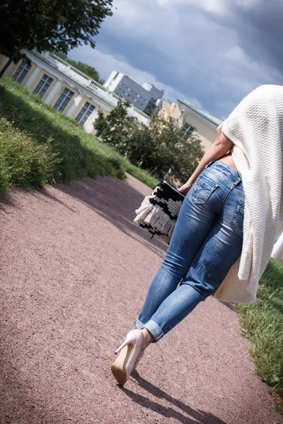 Donna posa sullo sfondo e palazzo in jeans scarpe, lungo cardigan. è tornata . — Foto Stock
