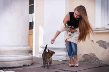 moda güzel genç ve güzel hipster kadın bir kedi ile oynarken, o uçan saç, eğildi.