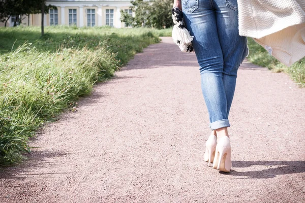 girl in jeans walking along the path of the camera, rear view, high heel shoes