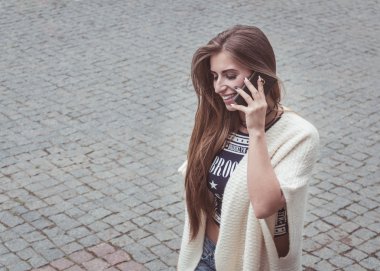 Genç kadın granit kaldırım zemin karşı cep telefonunda söz