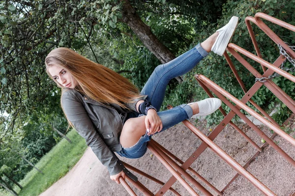 Jeune belle adolescente est assise sur des tiges en métal, parking vélo, rock n roll. style rock . — Photo