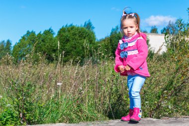 Pembe bir ceket, kot pantolon ve parkta yürüyüş botları, küçük kız