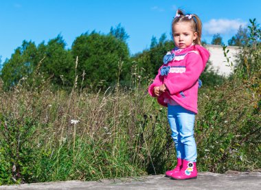 Pembe bir ceket, kot pantolon ve parkta yürüyüş botları, küçük kız