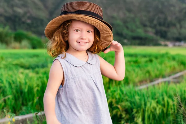 Child girl in straw hat. Cute kid looking at nature lanscape background. Adventure travel concept in retro style — Stock Photo, Image