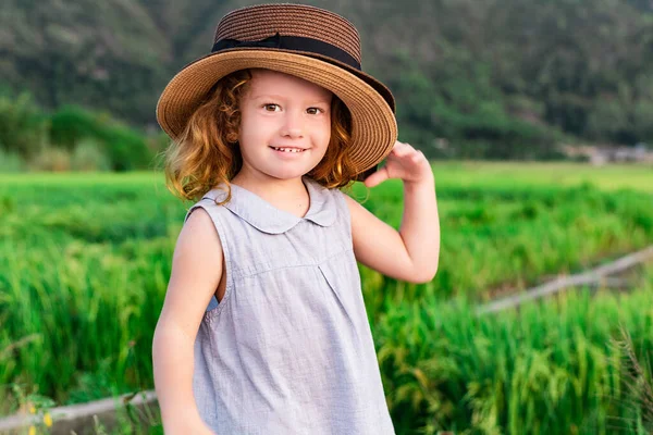 Κορίτσι με ψάθινο καπέλο. Χαριτωμένο παιδί που κοιτάει το φόντο του Λάνσκεϊπ. Περιπέτεια ταξίδια έννοια σε ρετρό στυλ Royalty Free Εικόνες Αρχείου