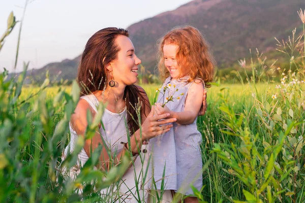 Genç anne ve kızı pirinç tarlası, doğa ve seyahat yakınında kucaklaşırlar.