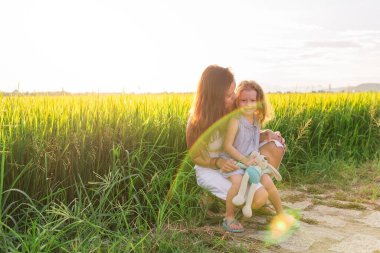 Genç anne ve kızı pirinç tarlası, doğa ve seyahat yakınında kucaklaşırlar.