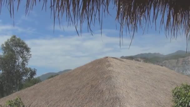 Rieten dak op een achtergrond van bergen en de blauwe hemel — Stockvideo