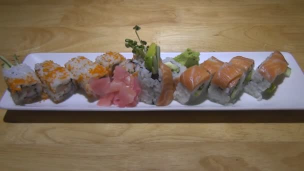 Lade van heerlijke sushi met zalm en vliegende vis roe ligt op tafel. een langzame stijging — Stockvideo