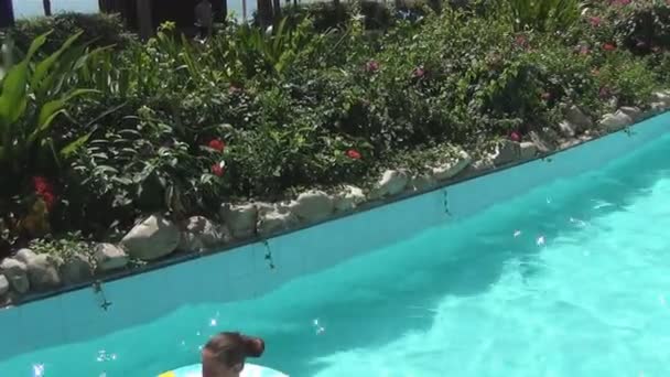 Due donne e il bambino sorridono e galleggiano su cerchi di nuoto su un fiume lento nel giardino tropicale — Video Stock