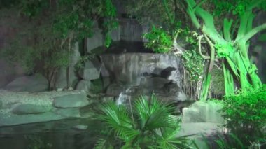 Güzel şelale ışık yeşil fener için alacakaranlıkta orman tarafından çevrili kayaların üzerinden akan