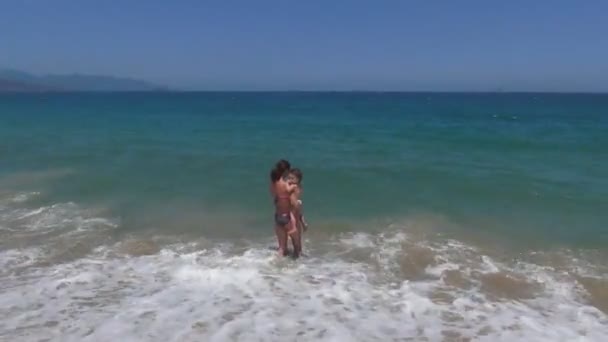 Молодая женщина с ребенком, пытающаяся уйти в бушующее море. море - это большая волна . — стоковое видео