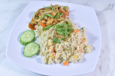 Tay usulü tavuklu pilav tabağı içinde görünür yumurta parçaları ve doğranmış havuç, yanında lezzetli bir kırmızı sosla birlikte bir porsiyon tavuk ve yeşil fasulye kızartması..