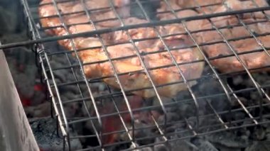 Sulu bir parça domuz eti tel askıda duruyor ve kömür ve ateşin üstünde kızarıyor.