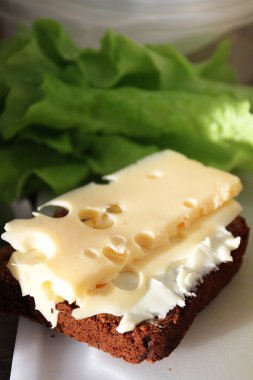 sandviç yeşil salata üzerinde siyah ekmek üzerinde peynir ve tereyağı ile