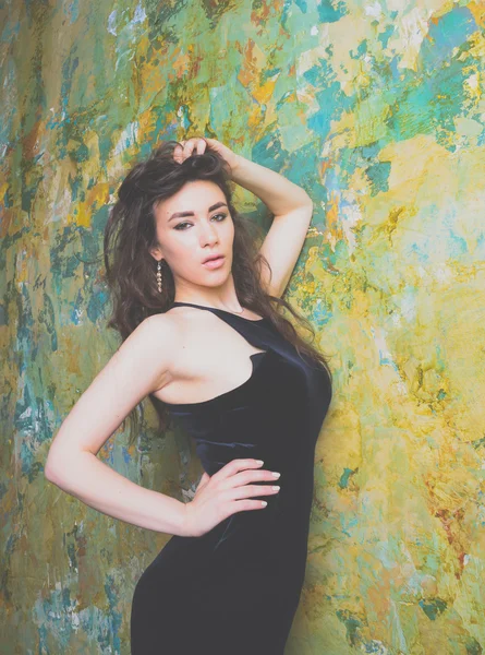 Chica en vestido negro posando cerca de la pared —  Fotos de Stock