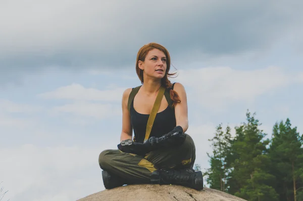 Hermosa chica militar sentada en una colina — Foto de Stock