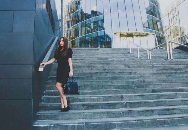 business girl in a black dress walks down the stairs