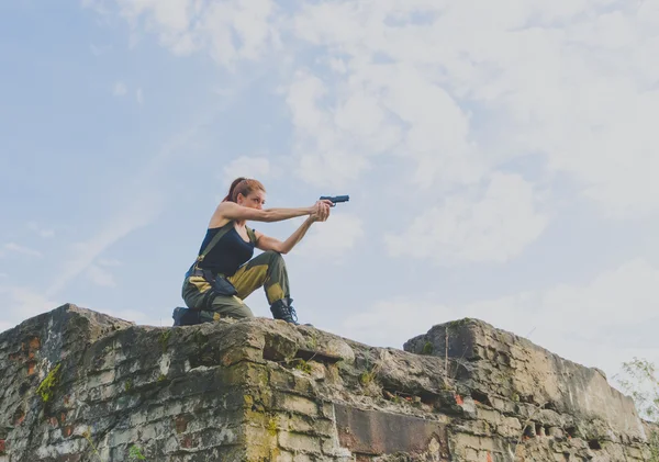 Soldater flicka med rött hår håller en pistol mot himlen — Stockfoto