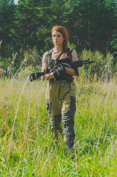 Дівчина з рудим волоссям виходить з лісу з пістолетом в руці — стокове фото