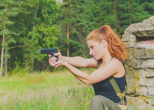 Девушка в форме ищет цель из пистолета — стоковое фото