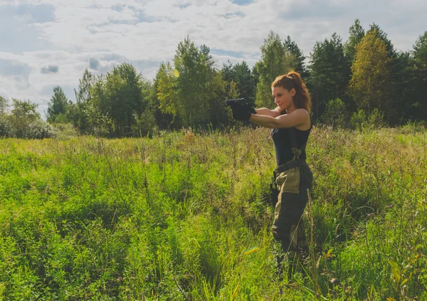 Chica peligrosa en uniforme con un arma lista para disparar — Foto de Stock