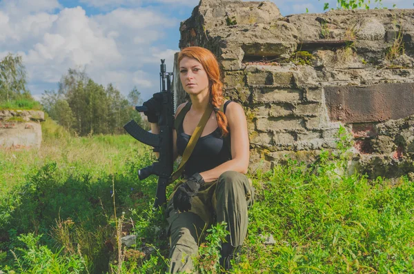 Den flicka soldaten med en pistol bredvid förstörde byggnader — Stockfoto
