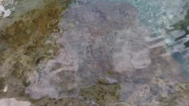 Ahogy egy férfi a sziklás parton sétál és elsüllyed a víz alatt. — Stock videók