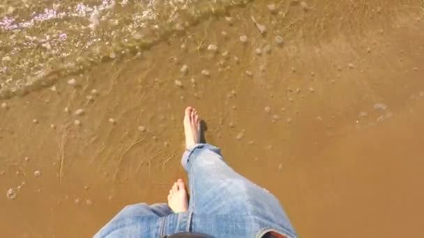 Мужские ноги в джинсах ходят по морю и песчаному пляжу — стоковое видео