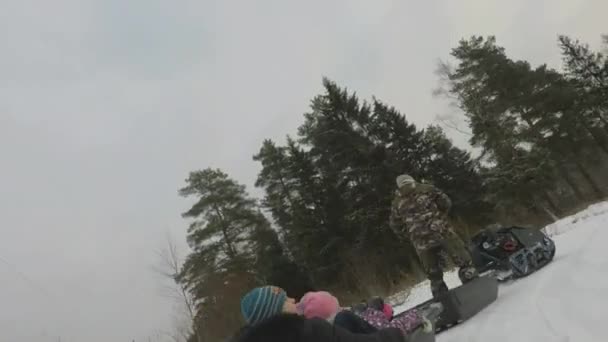 Взимку гусеничний трактор їздить дітьми на санях через ліс — стокове відео